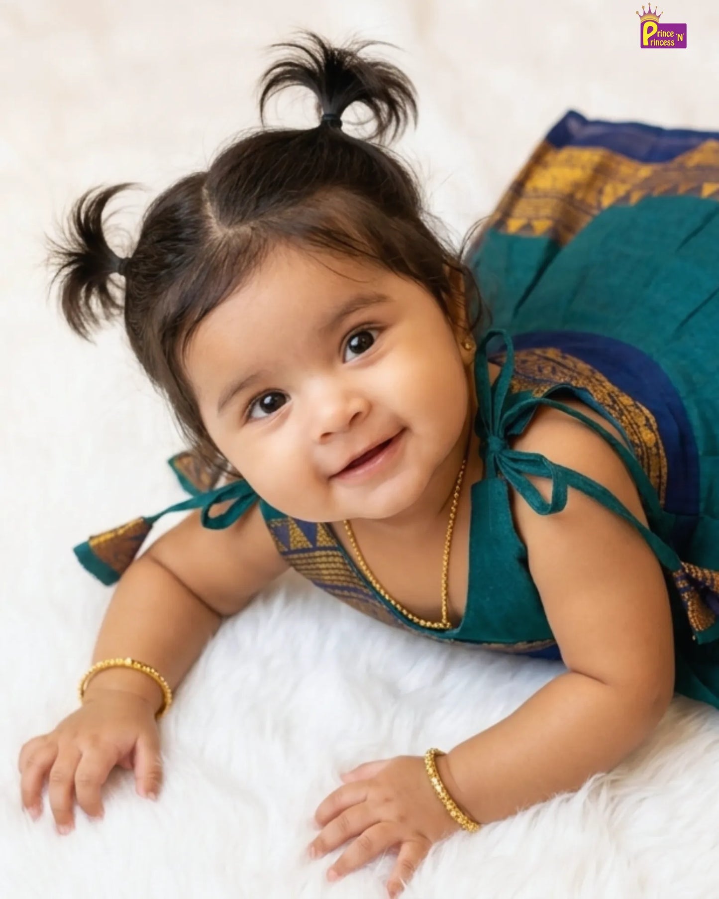 Baby in a traditional outfit lying on a white surface