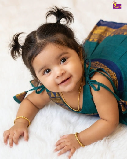 Baby in a traditional outfit lying on a white surface