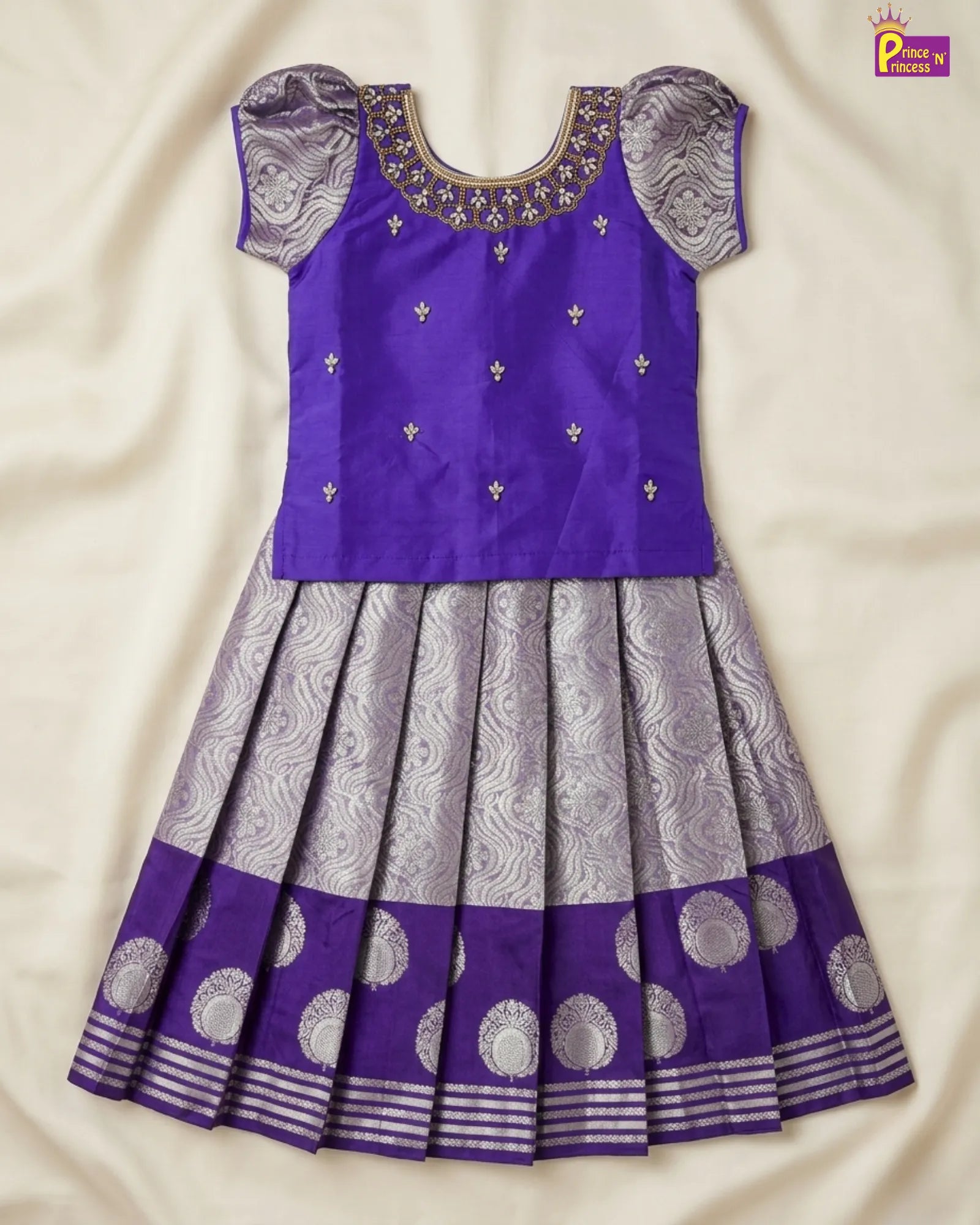 Purple and gray traditional dress with intricate patterns on a beige fabric background