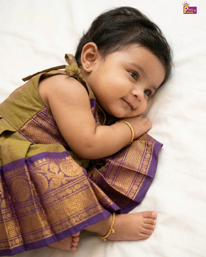 Baby wearing a traditional outfit with purple and gold patterns on a white background