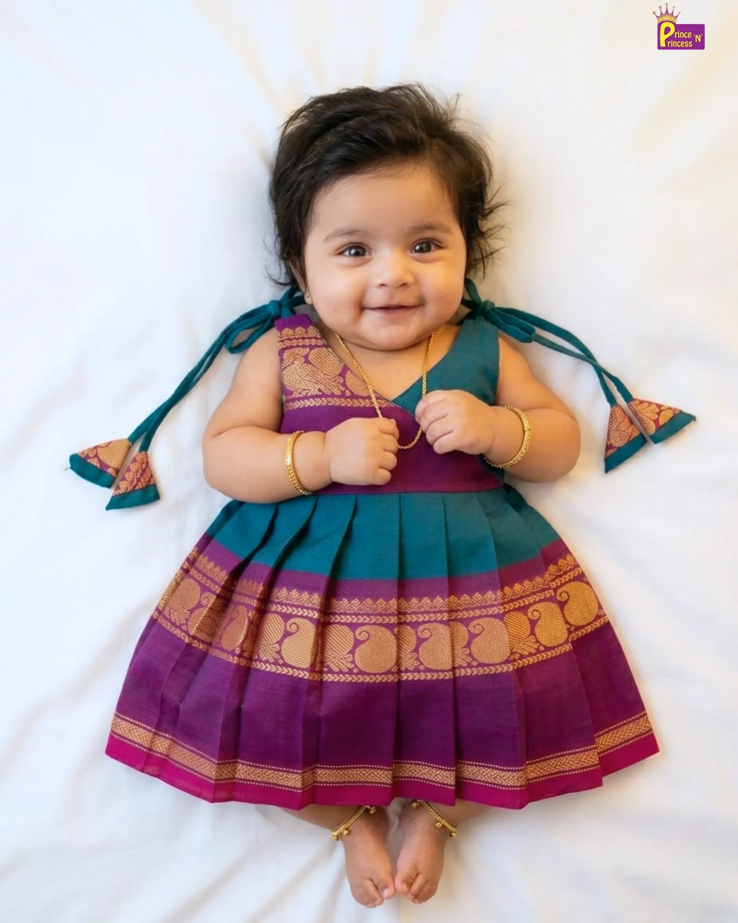Baby wearing a traditional outfit with purple and green colors on a white background