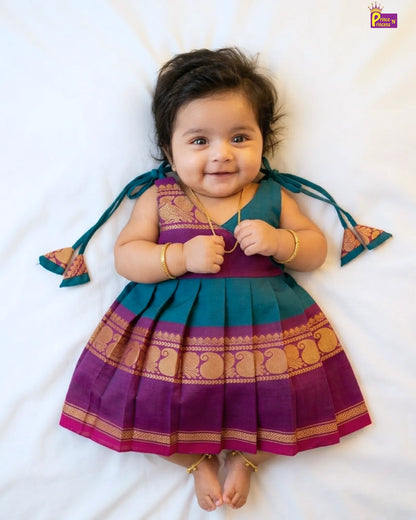 Baby wearing a traditional outfit with purple and green colors on a white background