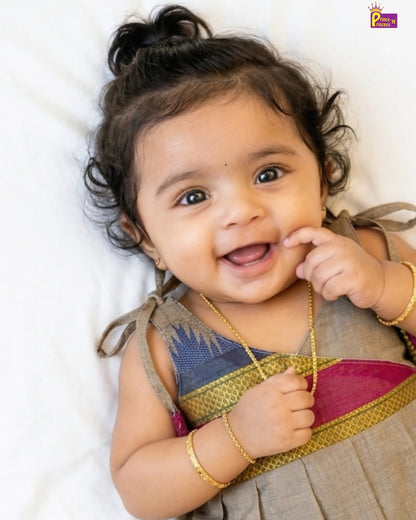 Baby wearing a traditional outfit with a plain background