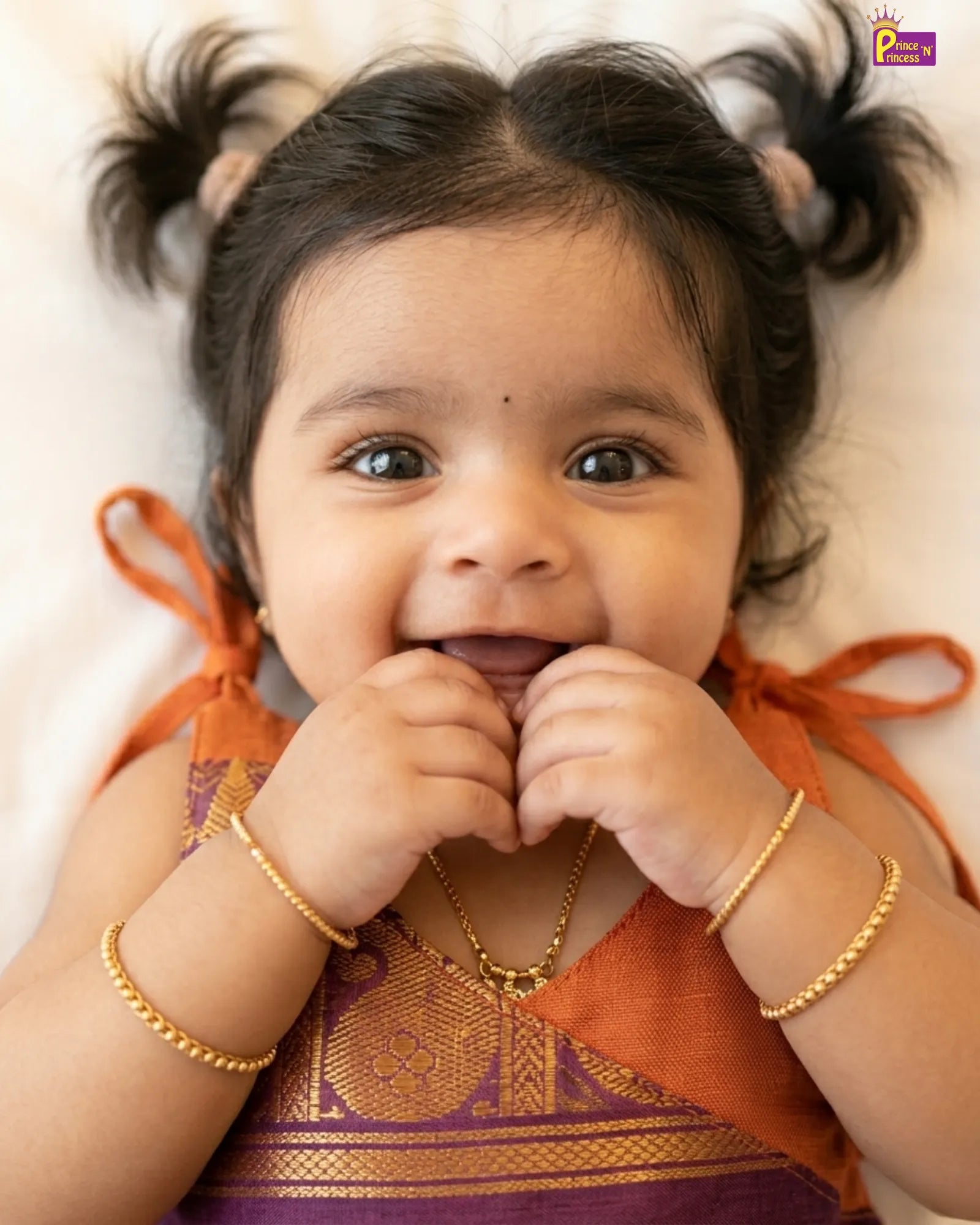 Child wearing traditional attire with gold jewelry on a white background