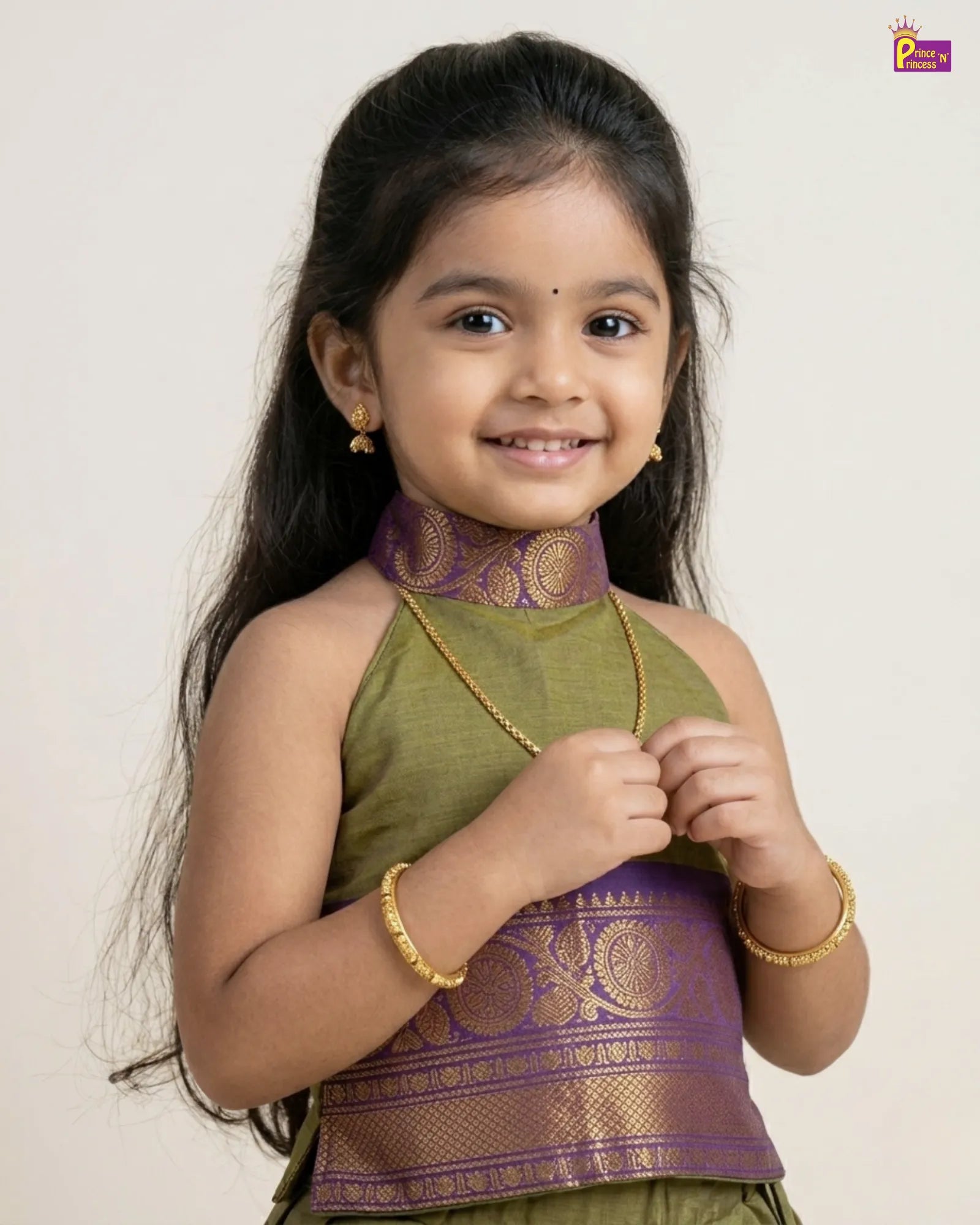 Young girl wearing a green and purple traditional outfit with a plain background