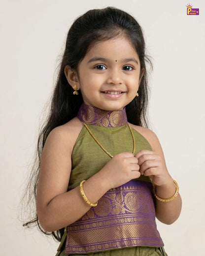 Young girl wearing a green and purple traditional outfit with a plain background