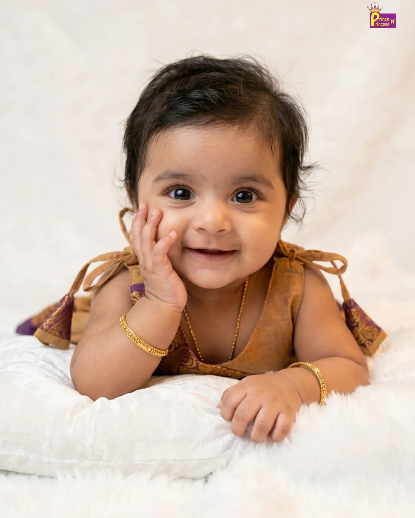 Baby wearing a traditional outfit with gold jewelry on a white background