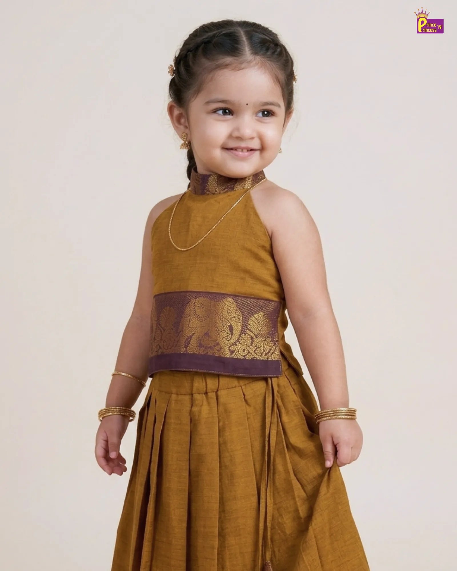 Young girl wearing a mustard yellow traditional outfit with a purple belt on a plain background