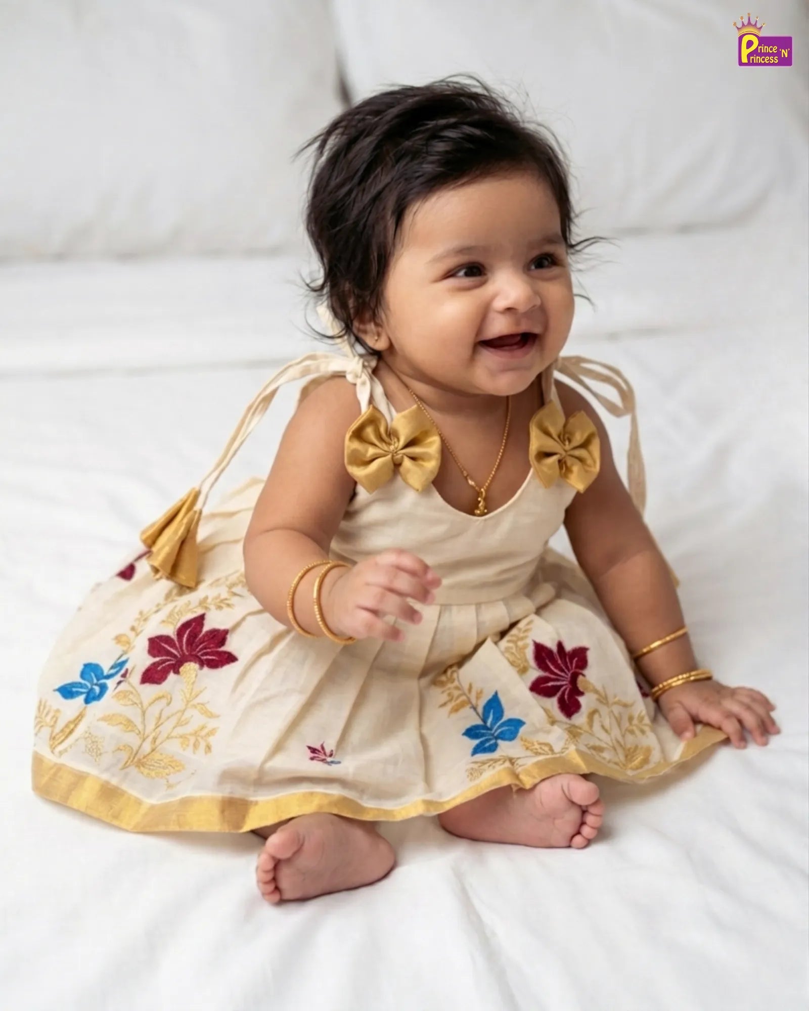 Baby girl in a traditional outfit with floral patterns on a white background