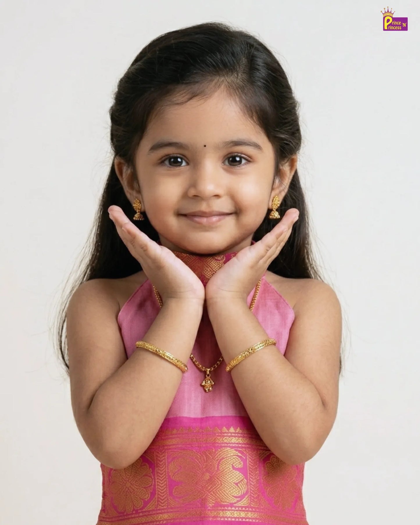 Young girl in a pink traditional outfit with gold jewelry on a white background