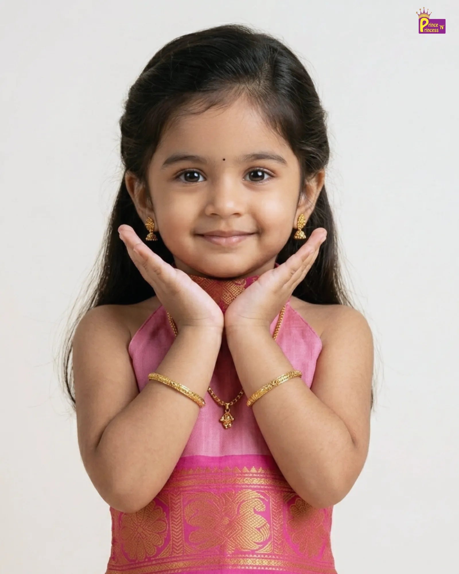 Young girl in a pink traditional outfit with gold jewelry on a white background