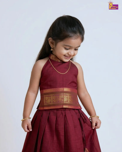 Young girl wearing a traditional maroon dress with gold accents on a white background