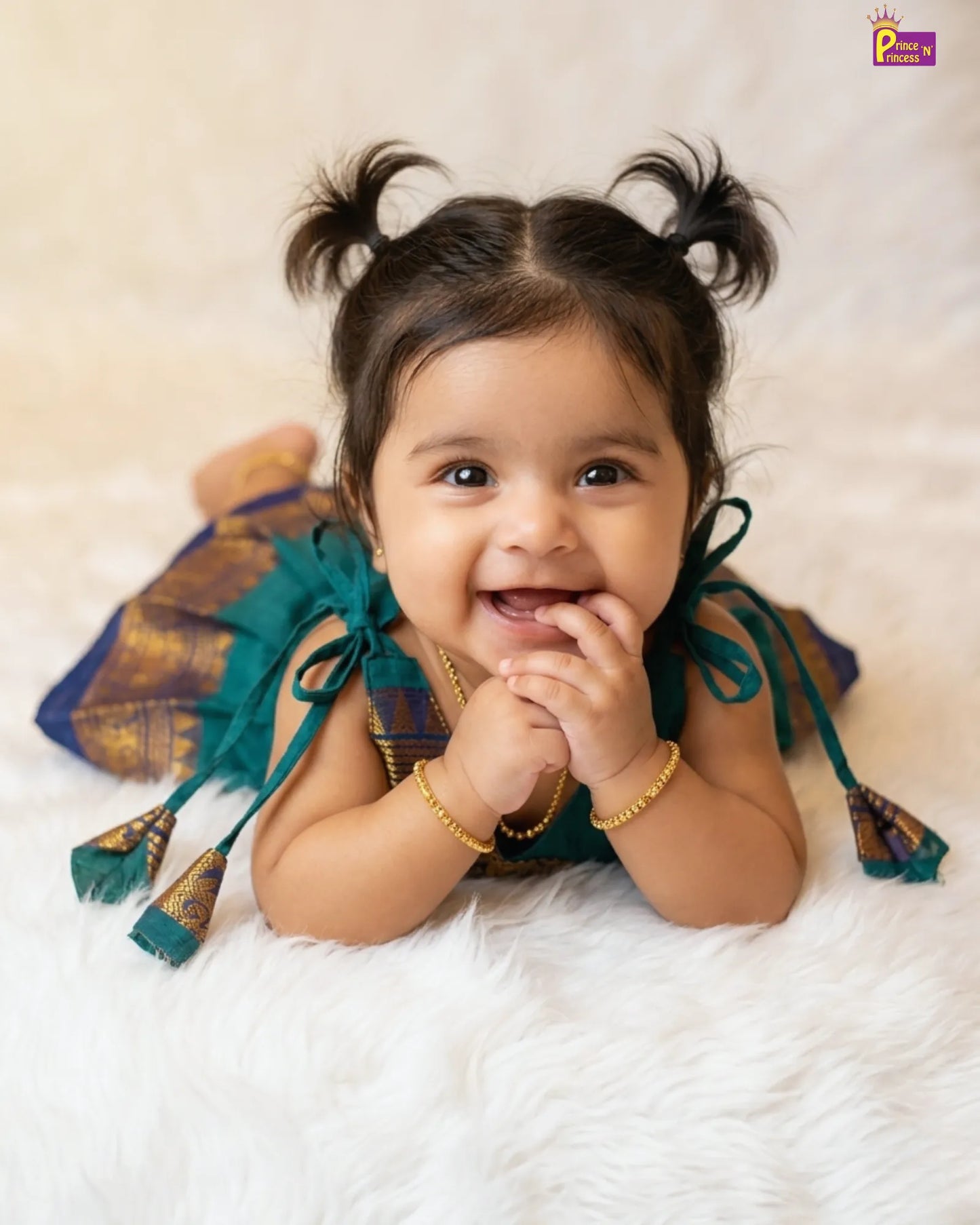Baby wearing traditional attire with decorative elements on a soft surface