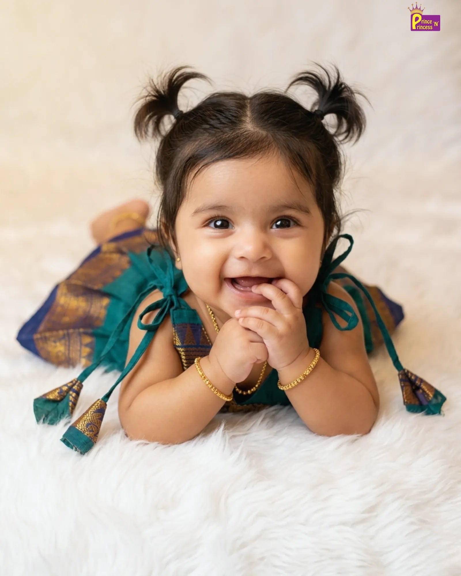 Baby wearing traditional attire with decorative elements on a soft surface
