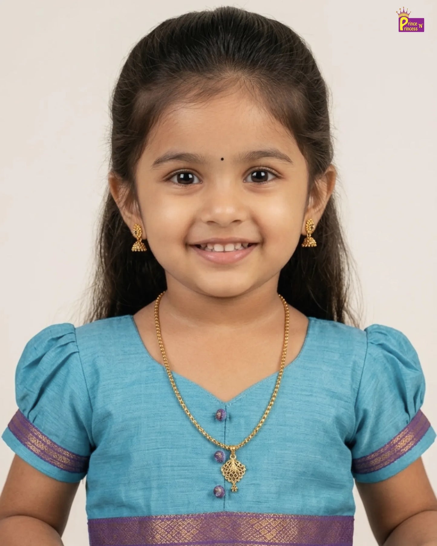 Young girl wearing a blue traditional outfit with gold jewelry against a plain background