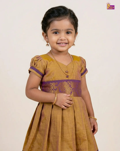 Young girl wearing a mustard yellow dress with purple accents on a plain background