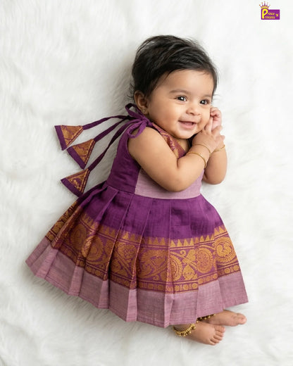 Baby wearing a traditional outfit with a purple and gold dress on a white background