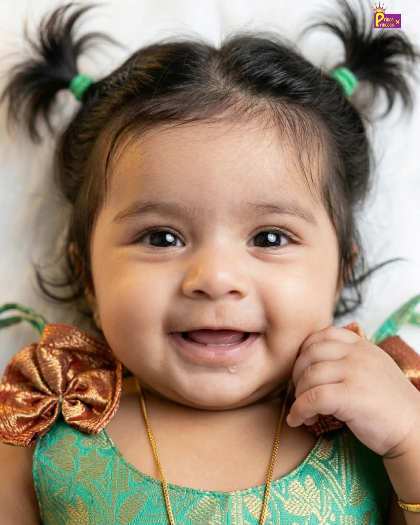 Child with braided hair and a large bow, wearing a green dress.