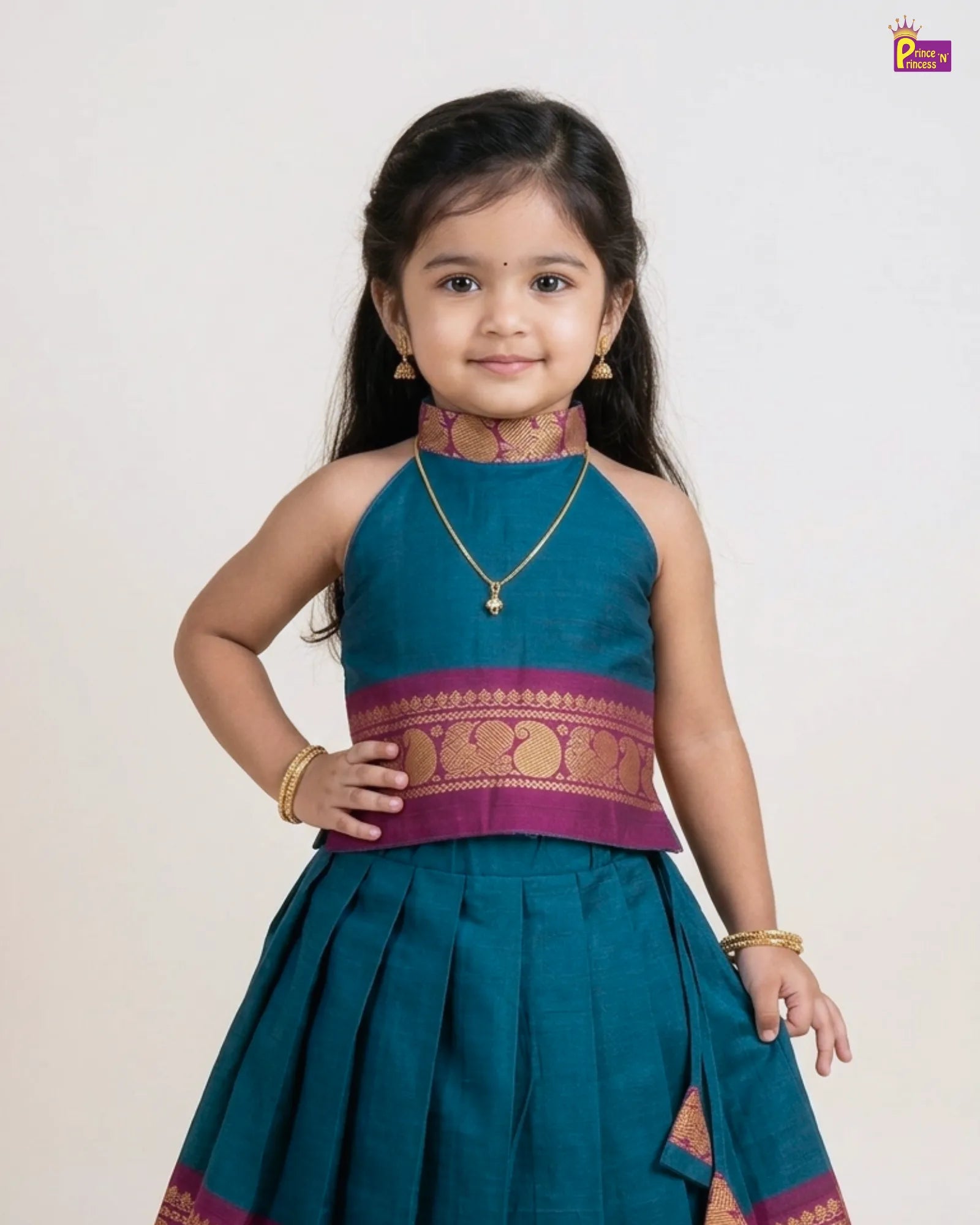 Young girl wearing a traditional teal and purple outfit with a plain background