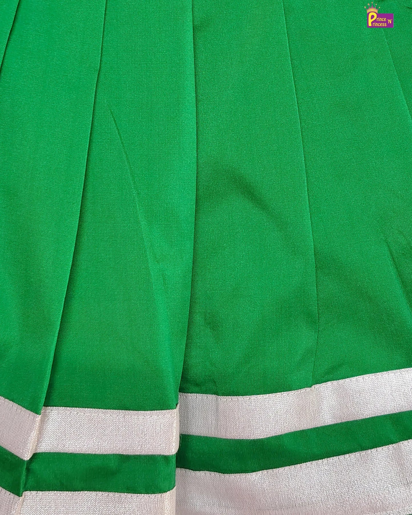 Close-up of a green fabric with white border, likely a sari or similar garment.