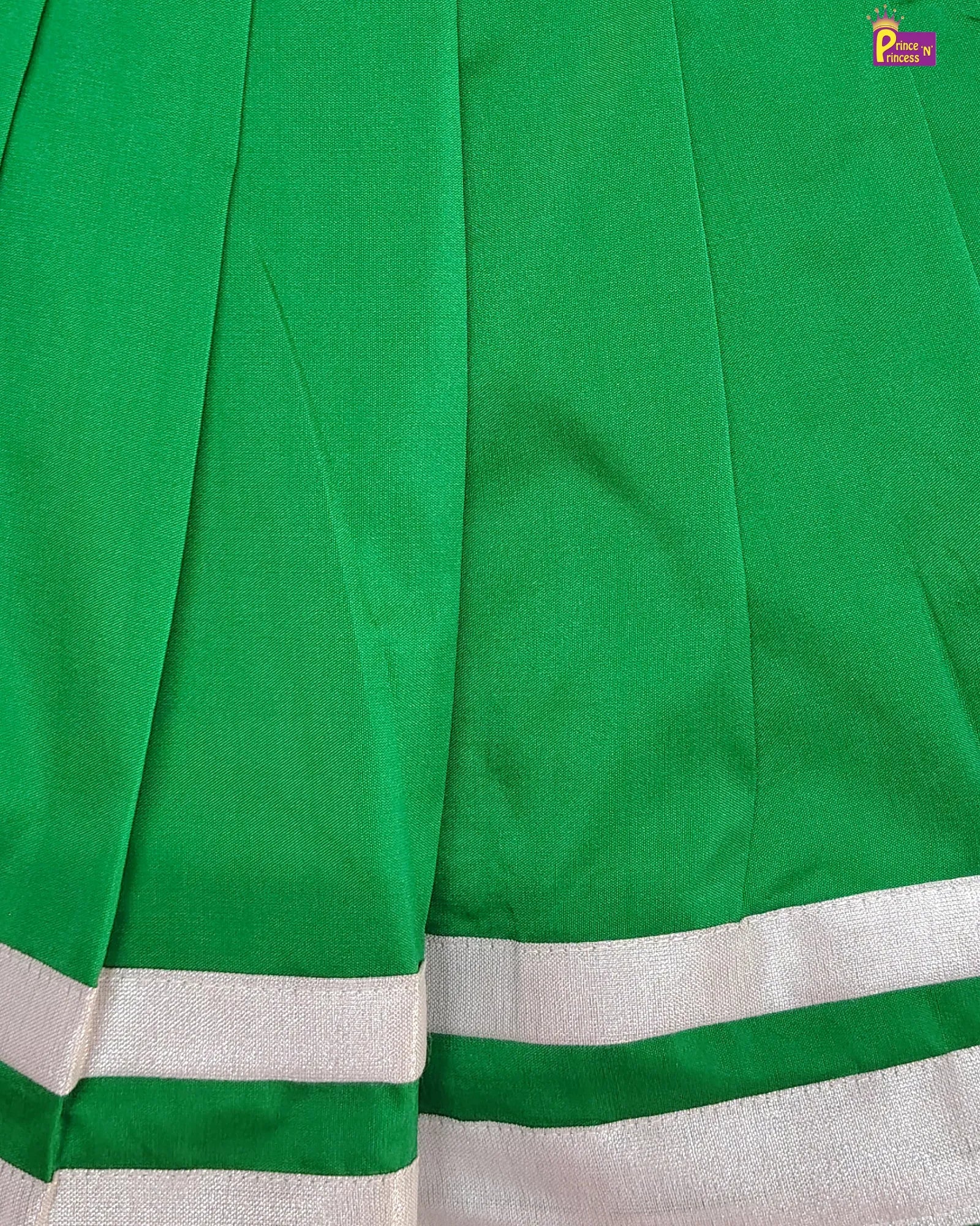 Close-up of a green fabric with white border, likely a sari or similar garment.