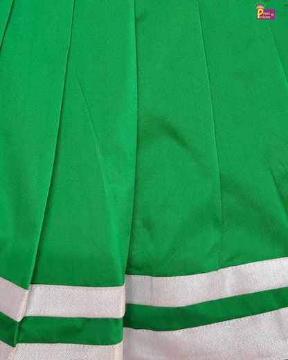 Close-up of a green fabric with white border, likely a sari or similar garment.