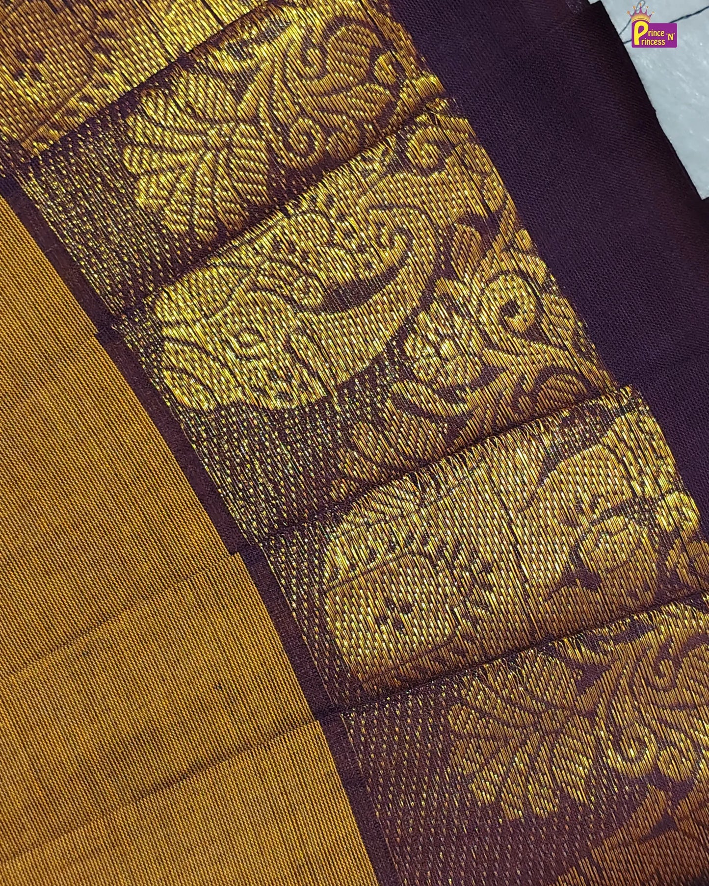 Close-up of a fabric with intricate gold pattern on a purple background