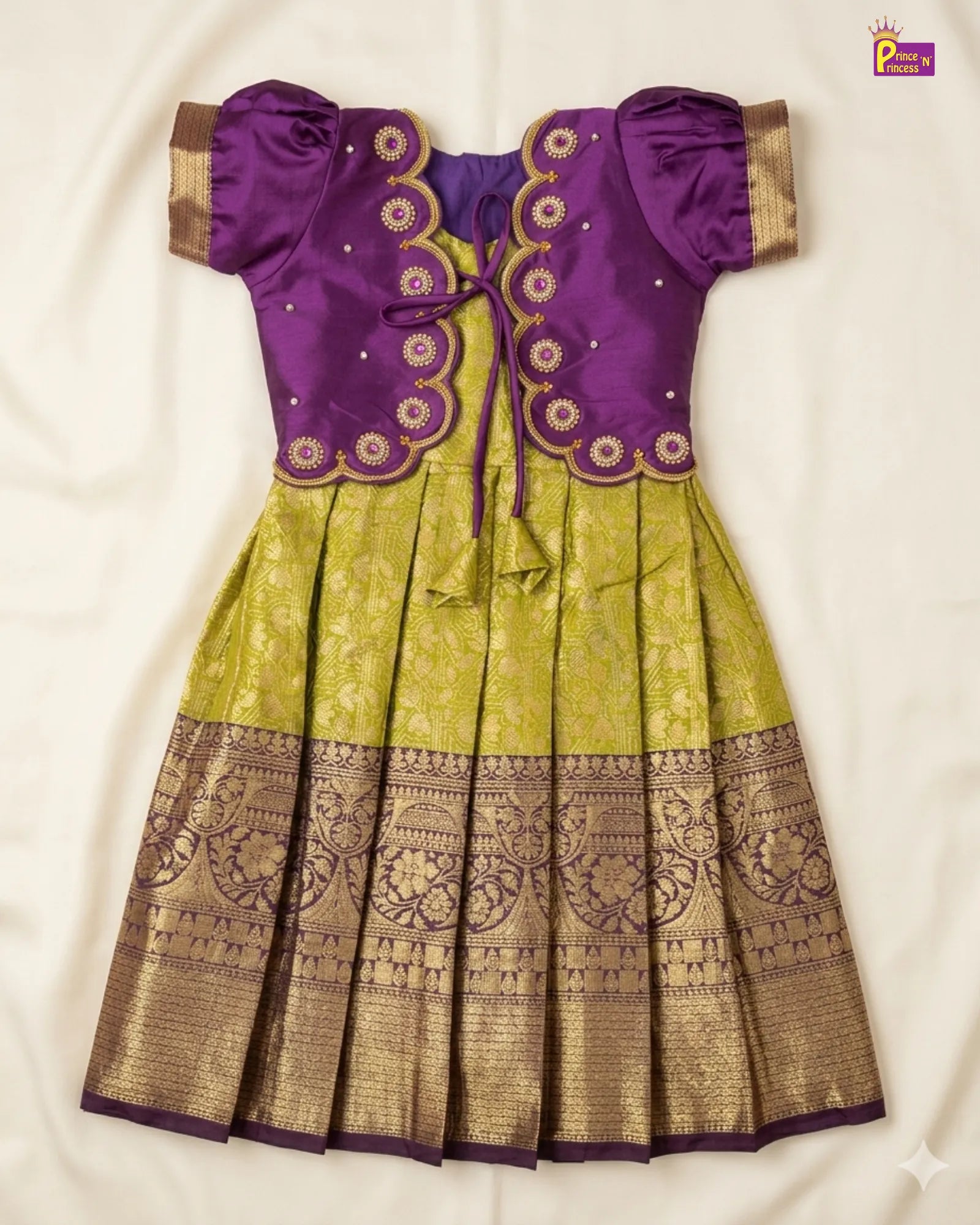 Traditional outfit with purple blouse and green and gold skirt on a white background