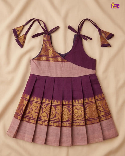 Purple and gold traditional dress with matching headband on a beige fabric background