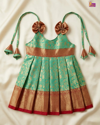 Traditional green and gold dress with decorative bows on a white background