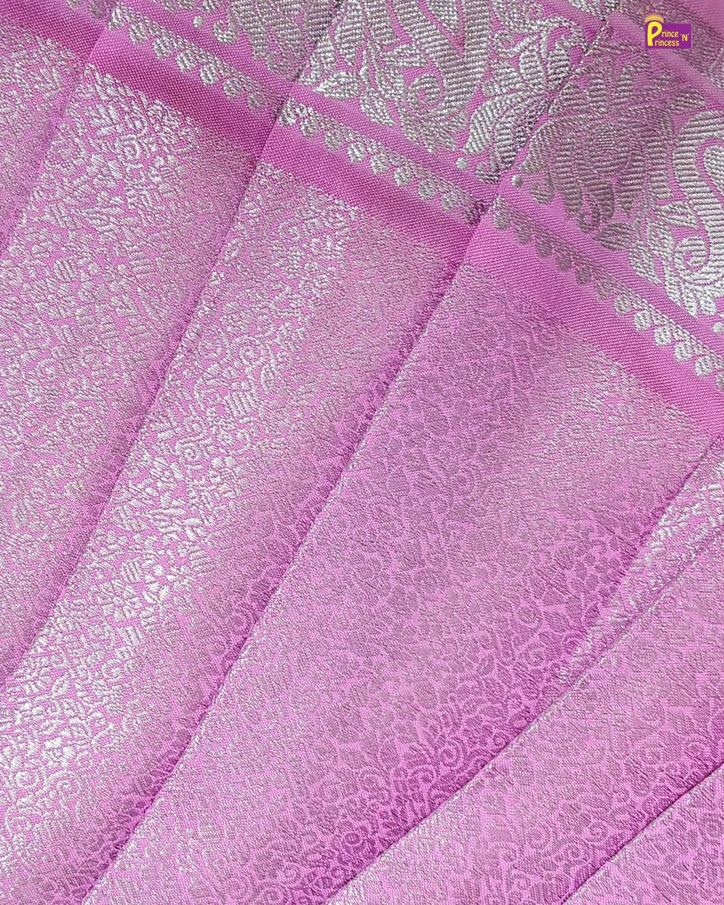 Close-up of pink fabric with intricate patterns and a brand logo in the corner.