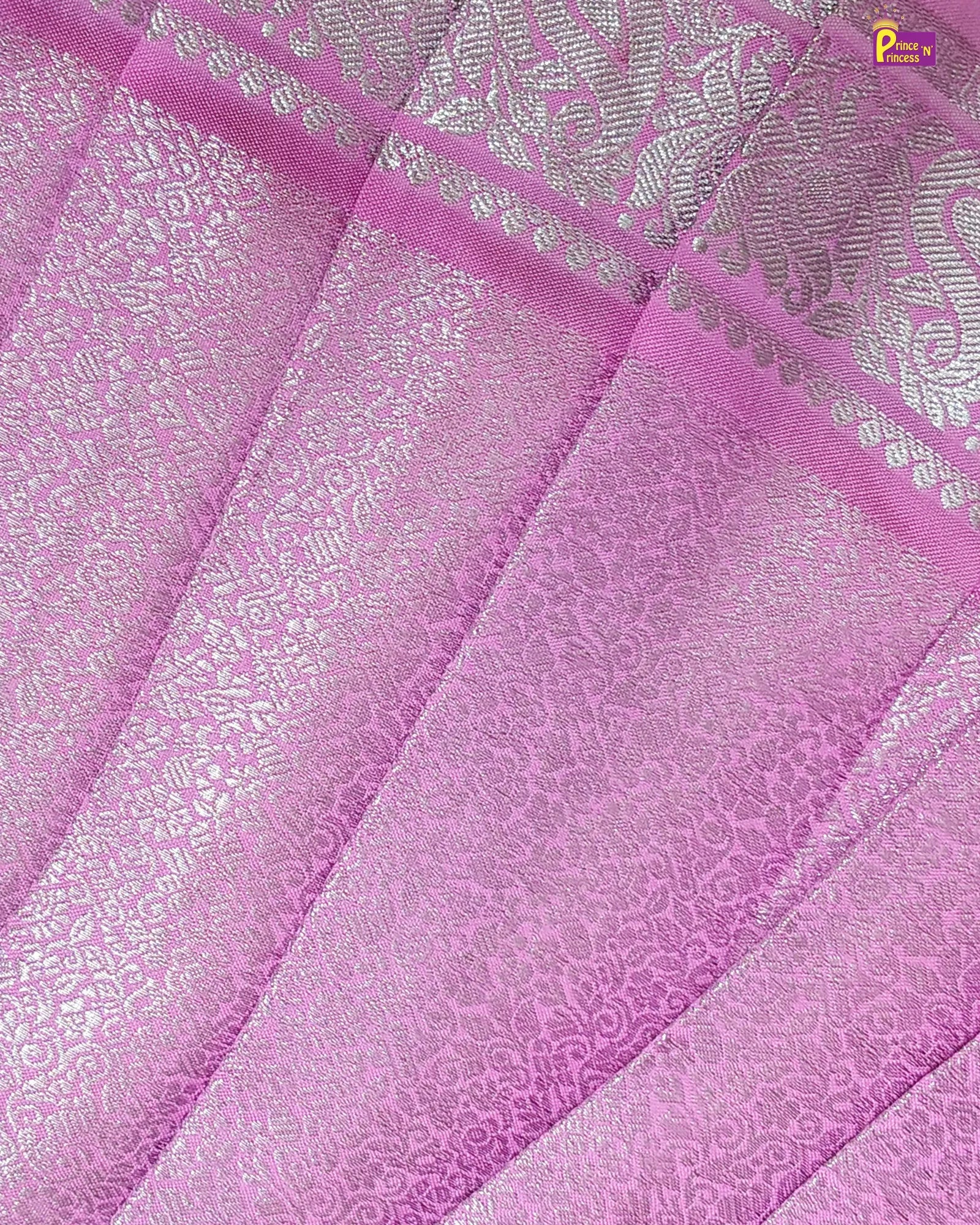 Close-up of pink fabric with intricate patterns and a brand logo in the corner.