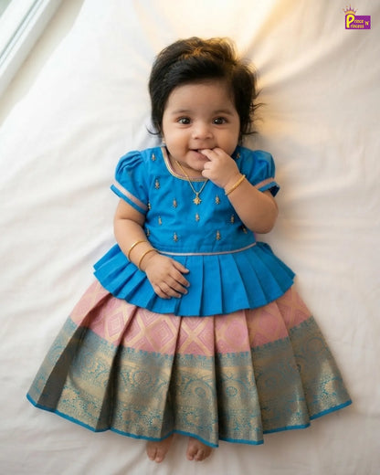 Baby wearing a blue and pink traditional outfit on a white background