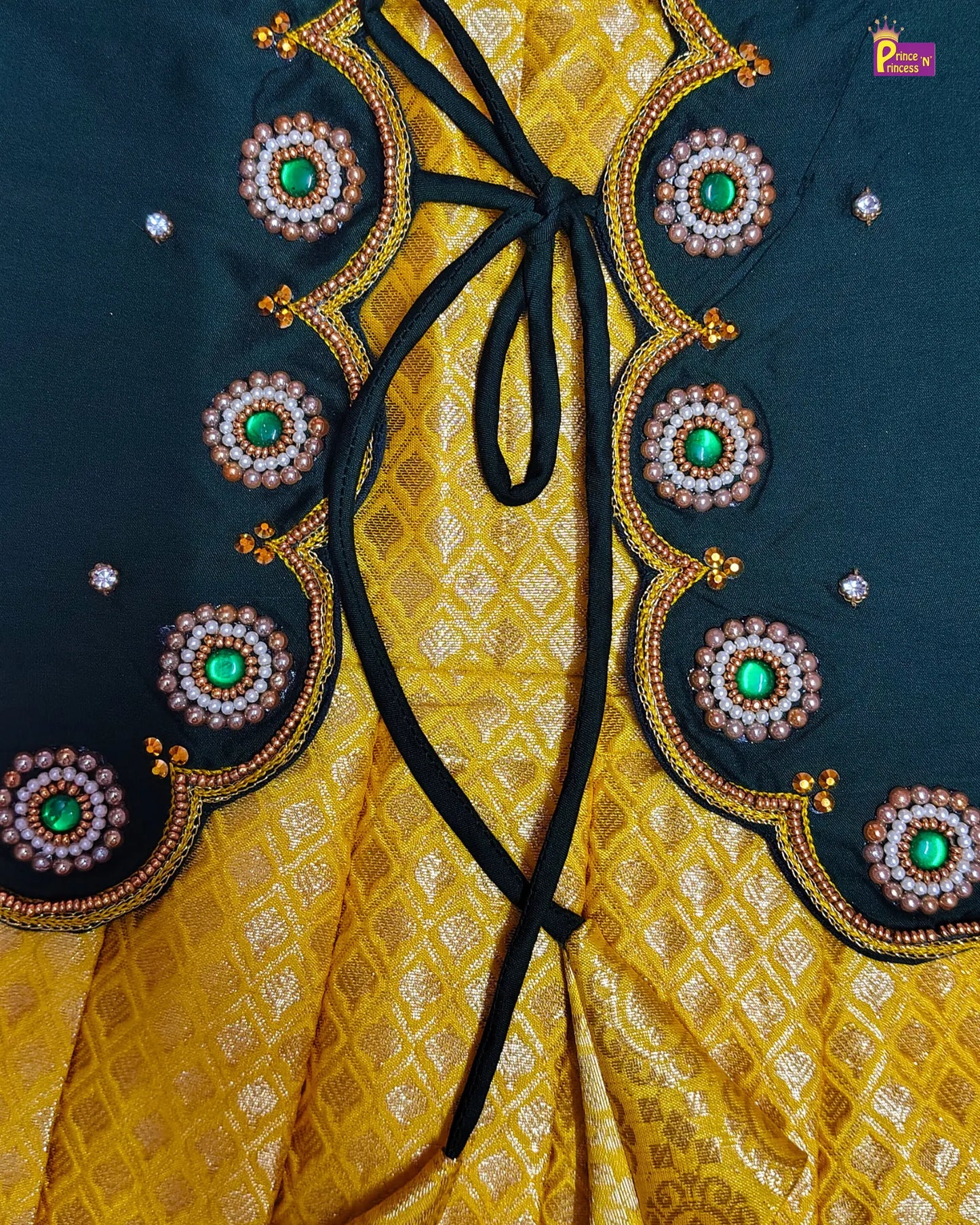 Close-up of a yellow fabric with black ribbon and decorative circular patterns on a dark background.