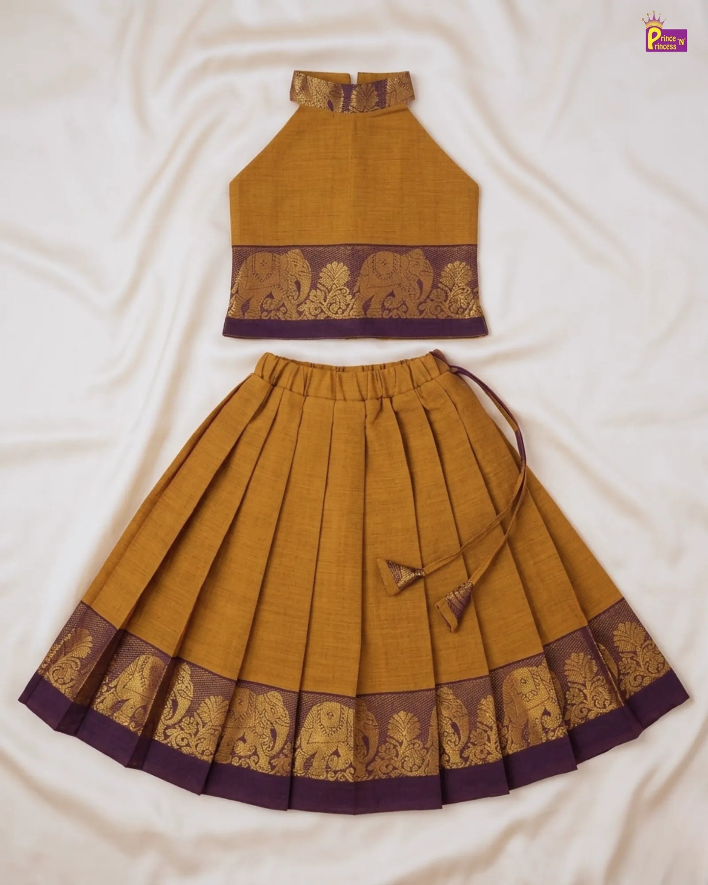 Mustard yellow and purple traditional outfit with elephant patterns on a white fabric background