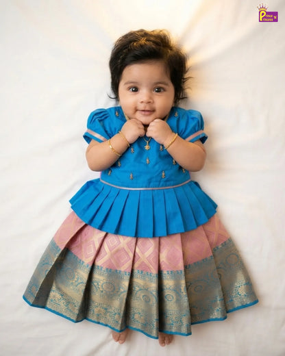 Baby wearing a blue and pink traditional outfit on a white background