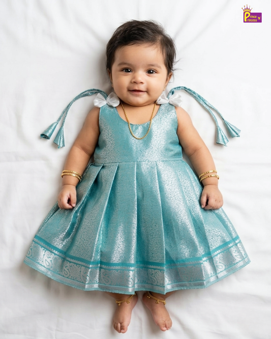 Baby wearing a blue dress with decorative sleeves on a white background