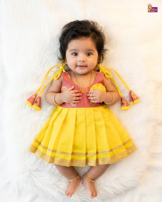 Baby wearing a yellow and pink dress on a white background