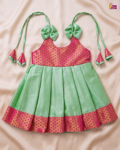 Green and pink traditional outfit with decorative bows on a beige background