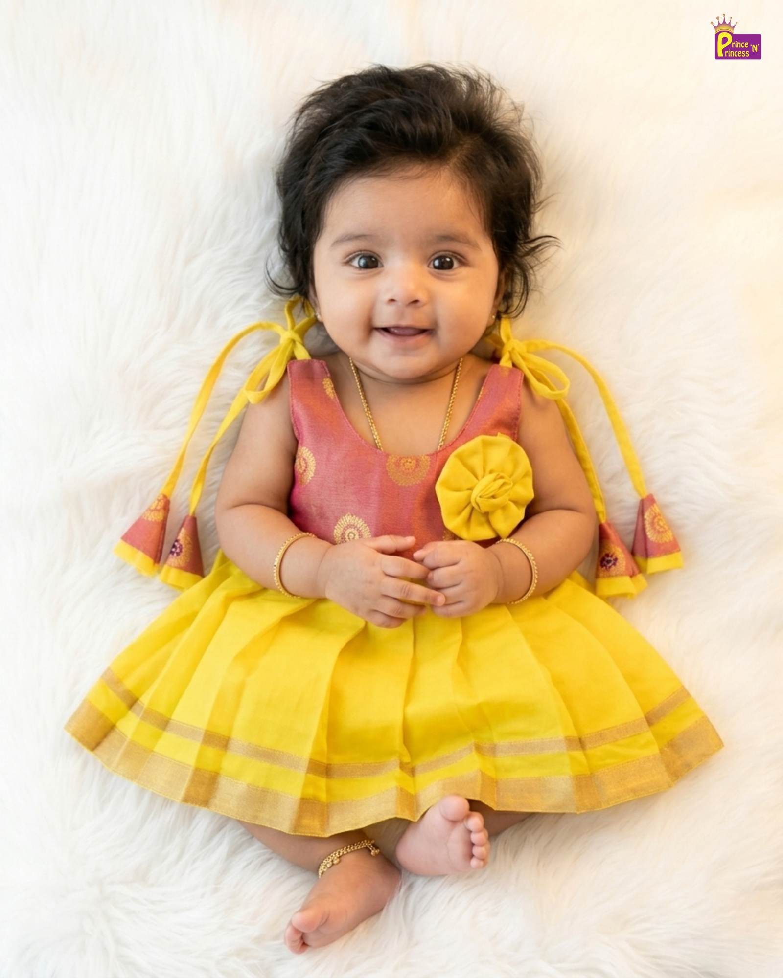 Baby in a yellow and pink dress with floral details on a white background