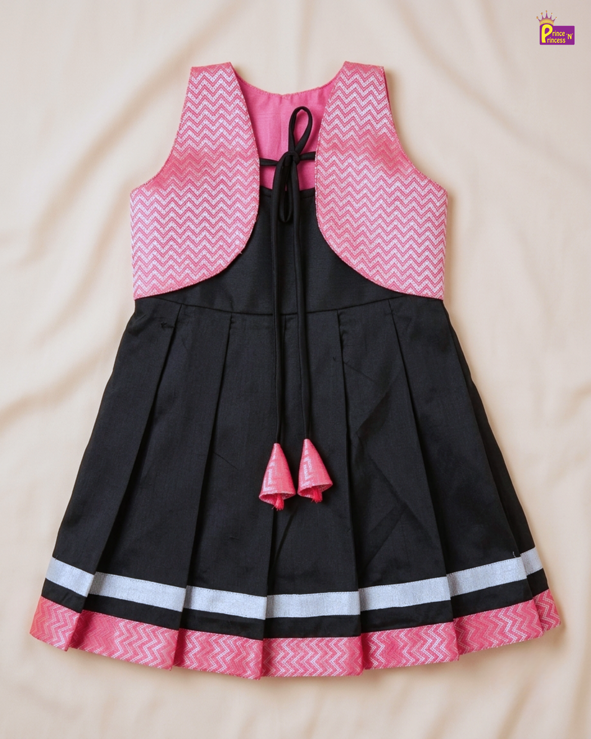 Black dress with pink and white patterned top on a beige background