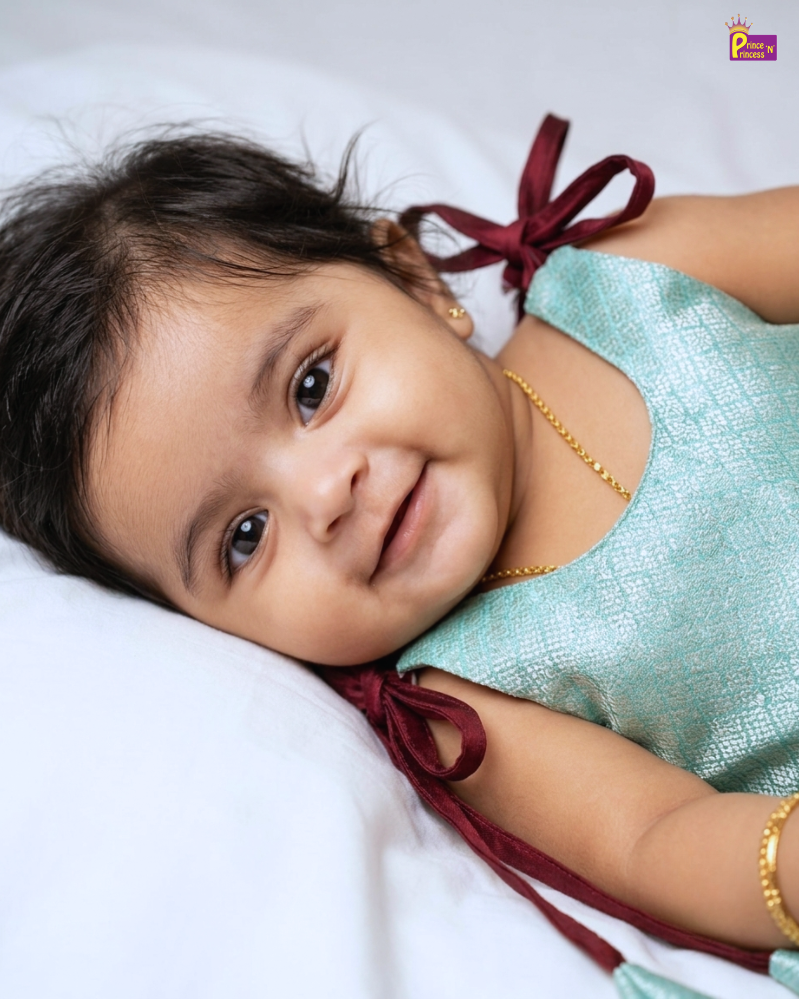 Young child wearing a light blue dress with red ribbons on a white background