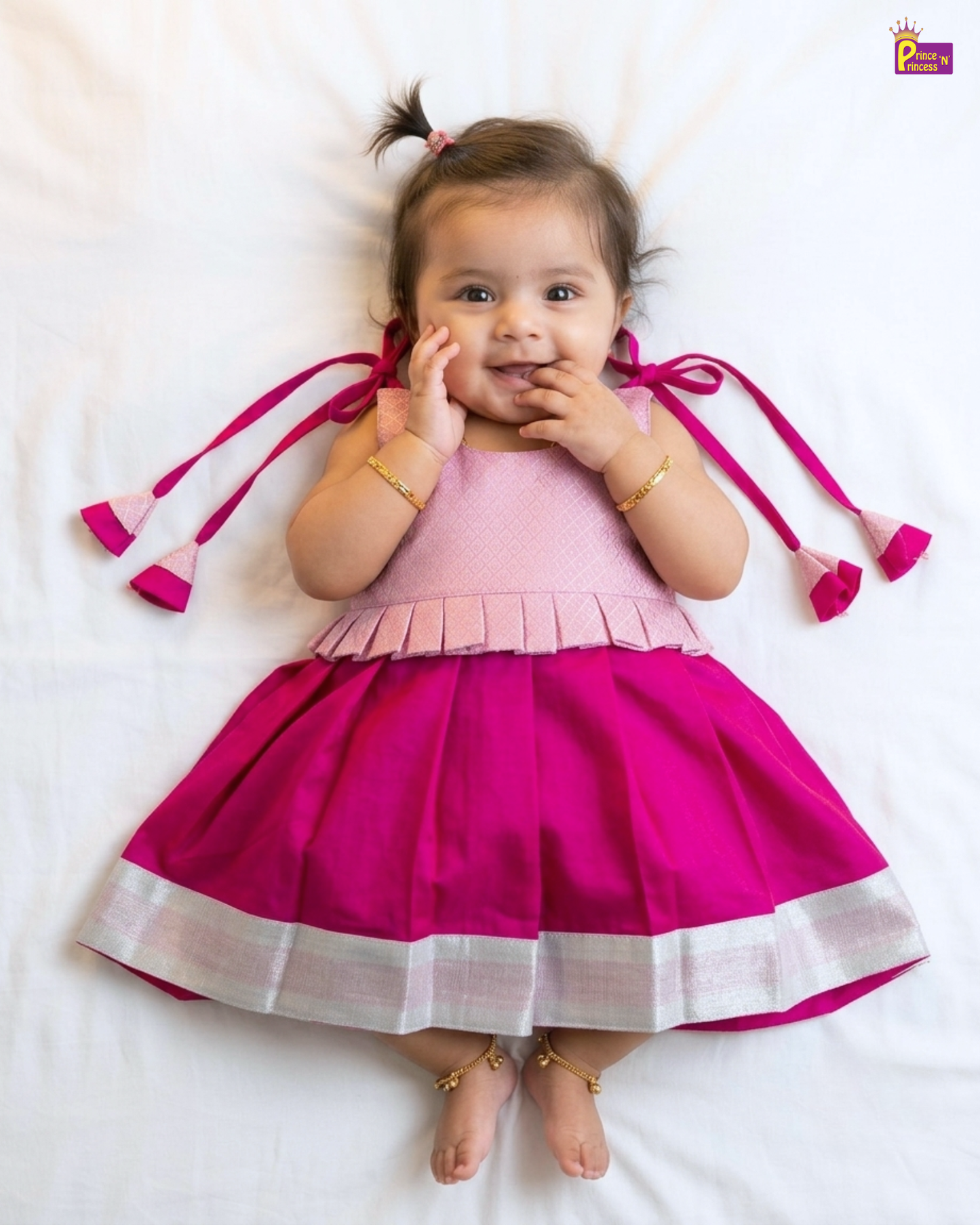 Child wearing a pink and magenta dress with decorative elements on a white background
