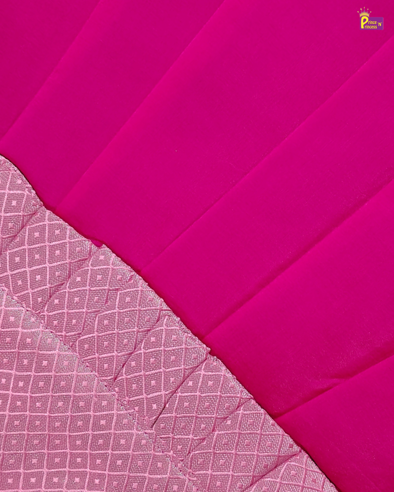 A close-up of a bright pink fabric with a lighter pink patterned border along the bottom left, showing the textile's texture and weave.