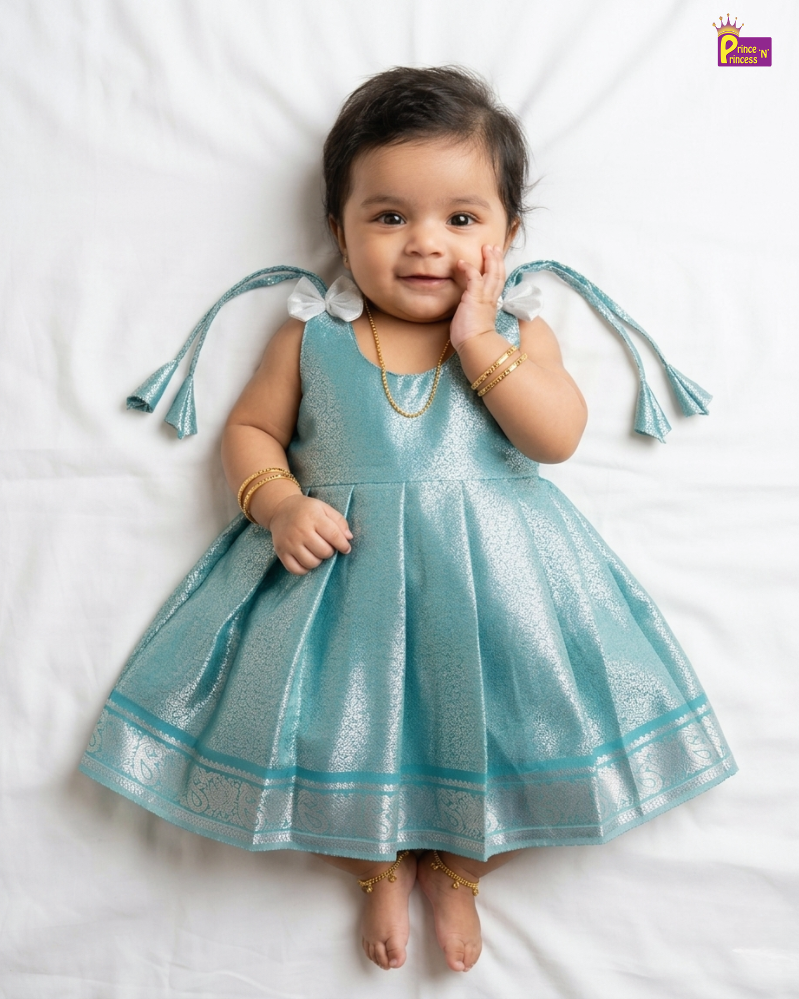 Baby wearing a blue dress with tassels on a white background