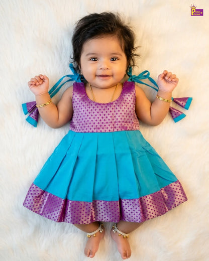 Baby wearing a colorful dress with blue and purple accents on a white background