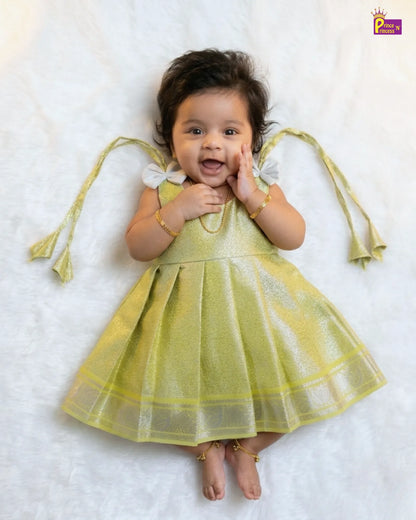 Baby in a yellow dress lying on a white surface