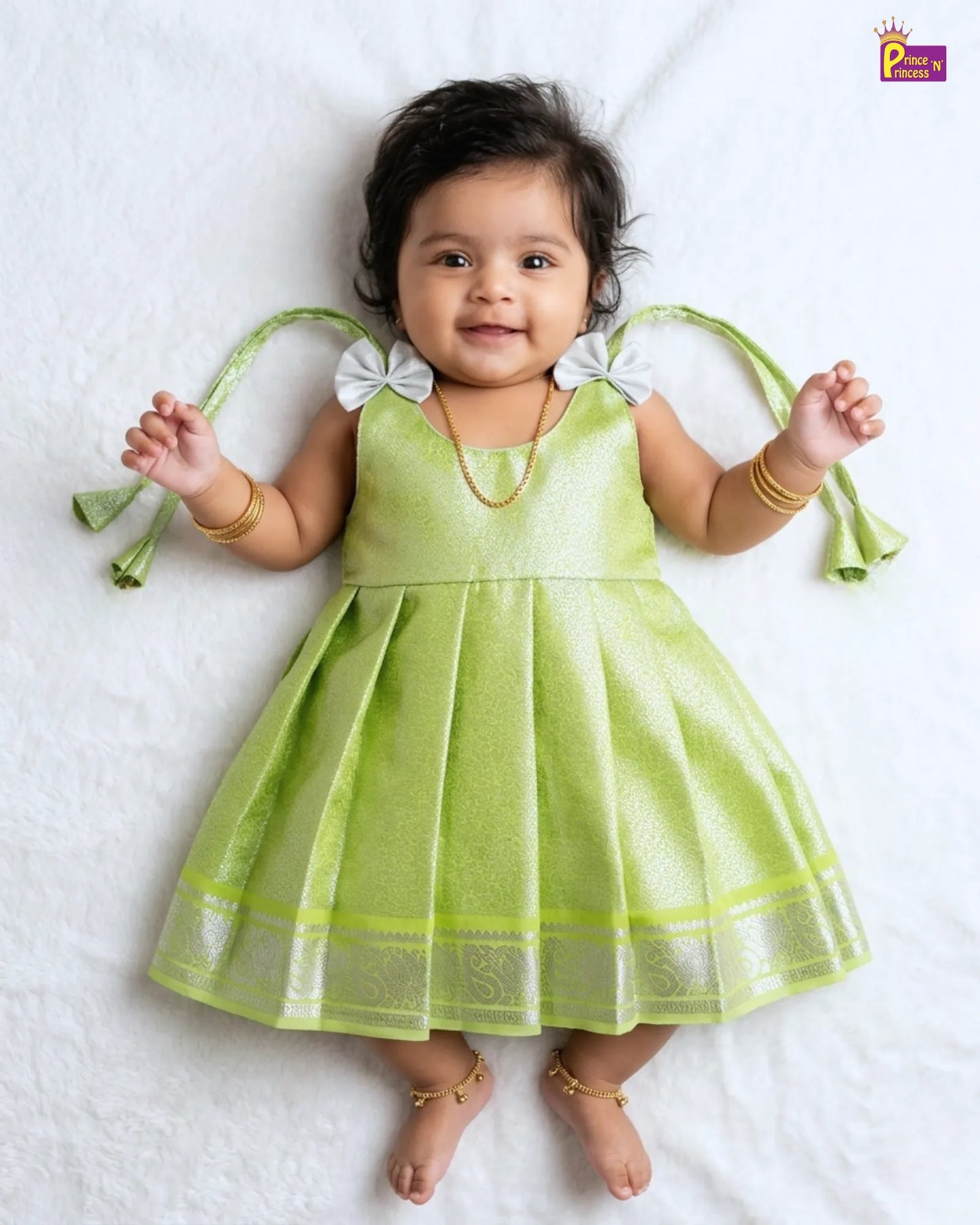 Baby wearing a green dress with white accents on a white background