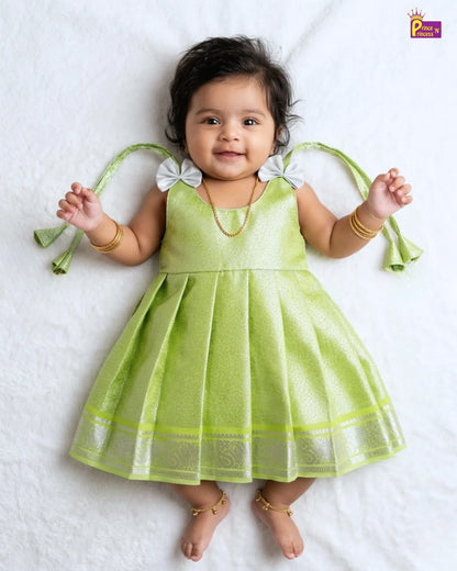 Baby wearing a green dress with white accents on a white background