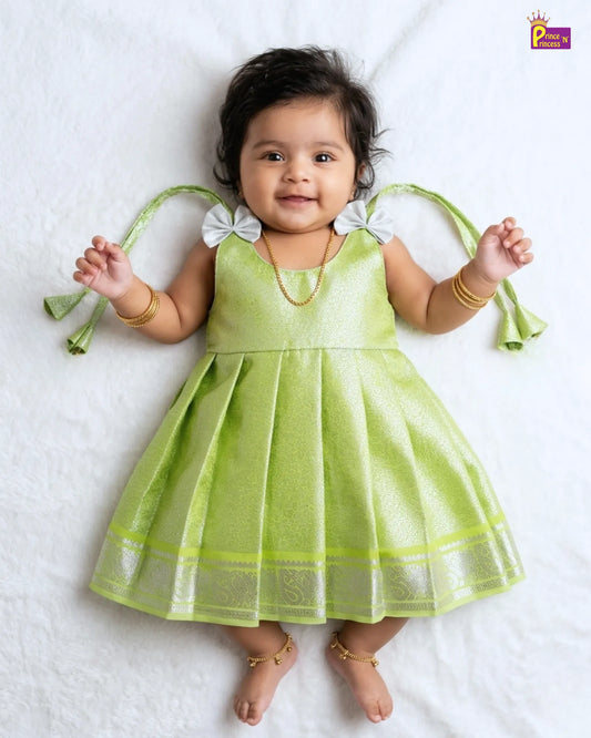 Baby wearing a green dress with white accents on a white background